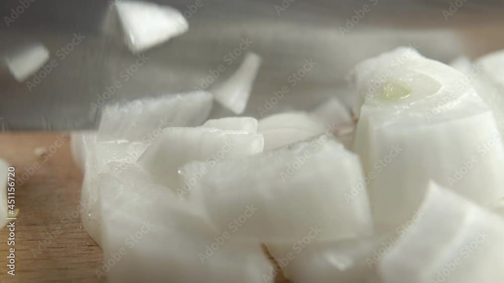 Chopping raw onion with a kitchen knife on a wooden cutting board. Macro shot. Cooking healthy vegetable food Chopping raw onion with a kitchen knife on a wooden cutting board. Macro shot. Cooking healthy vegetable food