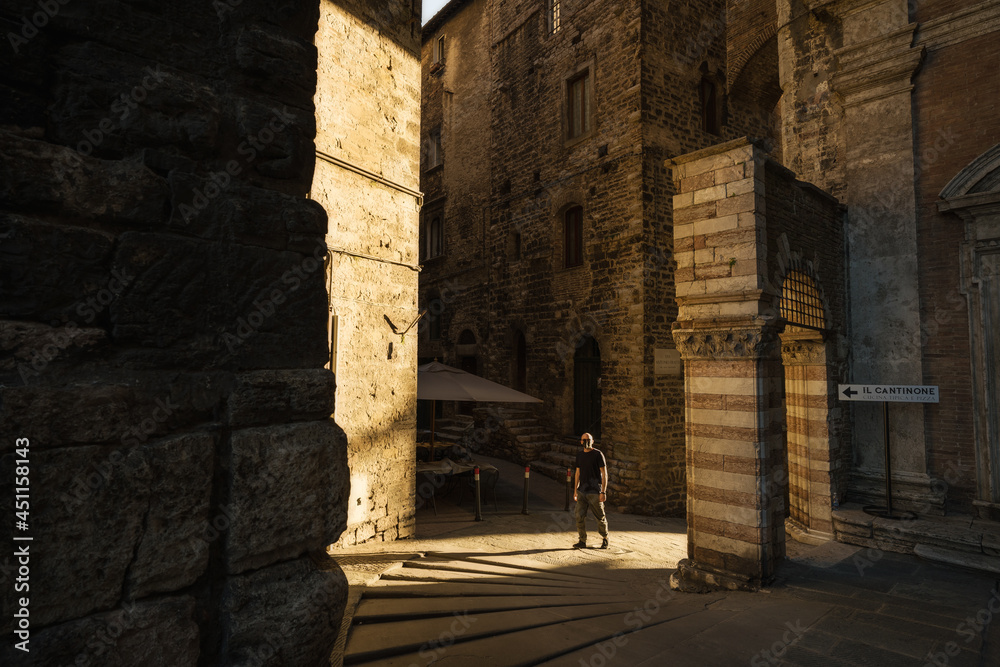 A young man walk into the streets of Perugia during sunset