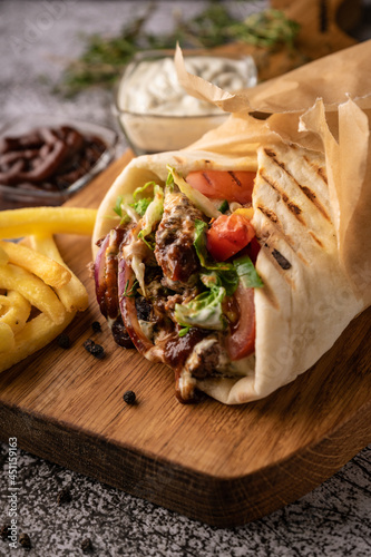doner kebab, a shawarma in a pit of fresh vegetables and meat. with large spices. restaurant serving. on a dark background. for menus and ads