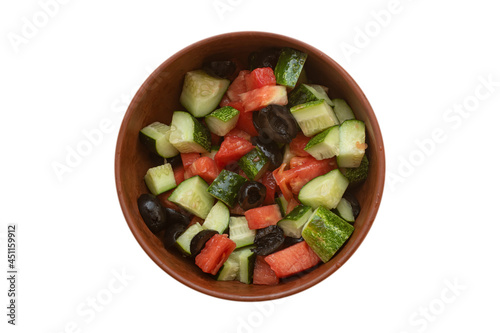 Top view on a bowl of homemade vegetable salad with tomatoes, cucumbers and black olives, isolated on white background.