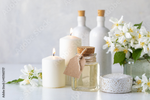 Spa concept with jasmine oil  with bath salt and flowers on a white background. Spa and wellness still life. Copy space.