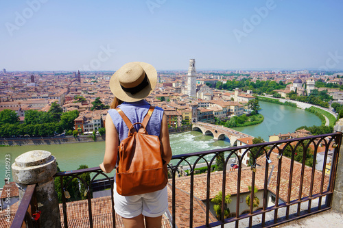 Romantic traveler girl visiting Verona city of love. Back view of young female backpacker enjoying cityscape of Verona, Italy.