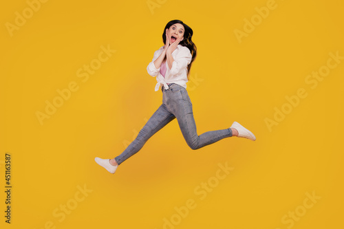 Portrait of funky amazed girl jump plams cheeks run on yellow background