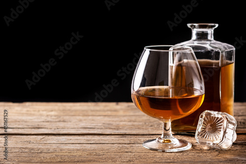 Cognac or whiskey drink on rustic wooden table and black background. Copy space 
