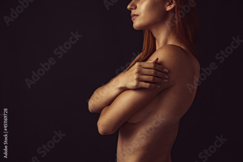 Portrait of young beautiful slim tanned red headed woman in lingerie posing isolated over dark studio background. Natural beauty concept.
