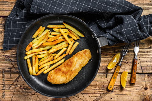 English Traditional Fish and chips dish with french fries in a pan. Wooden background. Top view