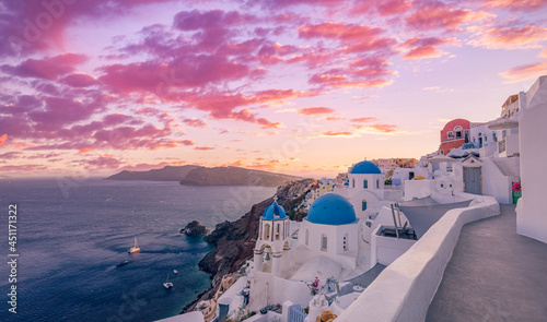 Beautiful panorama view of Santorini island in Greece at sunrise with dramatic sky. Stunning Oia cityscape, sunset colors sky with blue domes with white architecture. Amazing travel vacation landscape