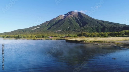 Movement over the surface of the lake and the edge of the shore. A volcanic mountain on the background. Kamchatka, Russia.