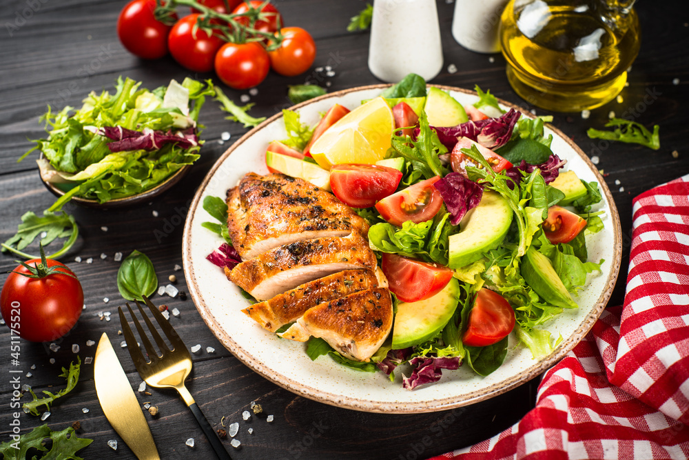Healthy food concept. Grilled chicken with fresh salad at dark wooden table.