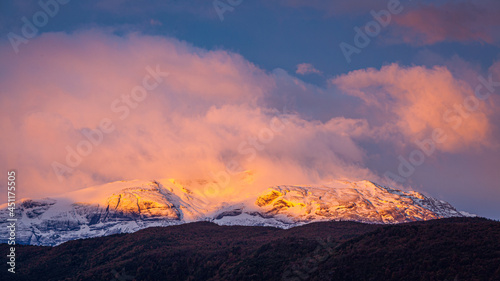 Autumn in Patagonia: sunrise over snow covered mountains shrouded in clouds