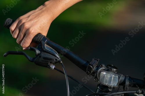 Woman's hand clutching the handle of a bicycle in the bright sunlight on a summer day close-up with copy space