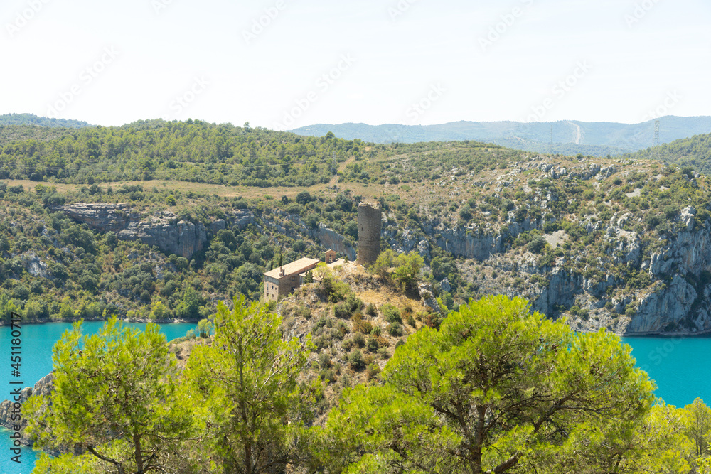 landscape of the Grado reservoir in Huesca Spain where you can see a hermitage destroyed by time surrounded by mountains and water