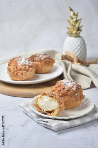 luxury home made chilled vanilla cream puff pastry choux with sugar powder on wood plate and cloth in white marble background dessert halal menu