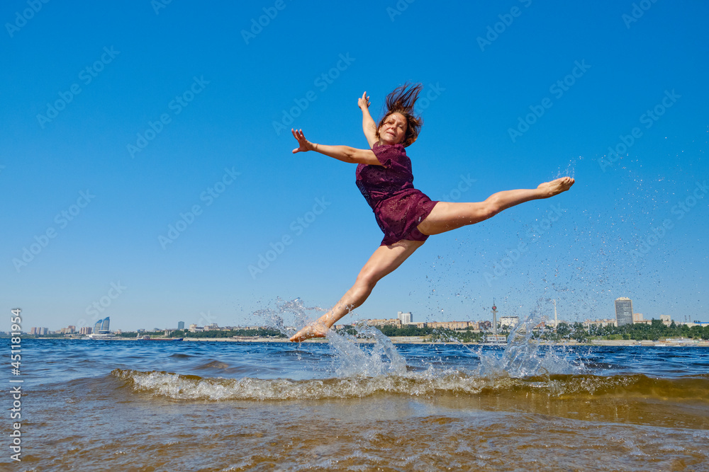 Striving for high goals through overcoming yourself. Jumping on the beach in the water.