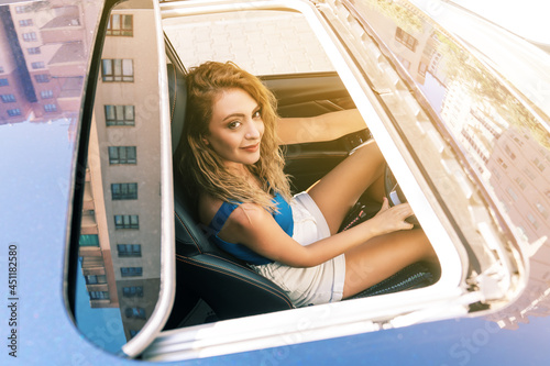 Top view from sunroof of a young beautiful woman sitting on car seat and drive carefuly.  photo