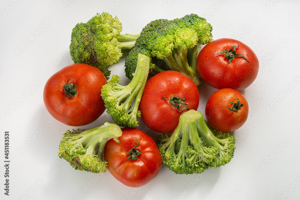 Ripe red tomatoes and broccoli slices on a white background. Harvest in the fall. Isolated Ripe red tomatoes and broccoli slices on a white background. Harvest in the fall. Isolated