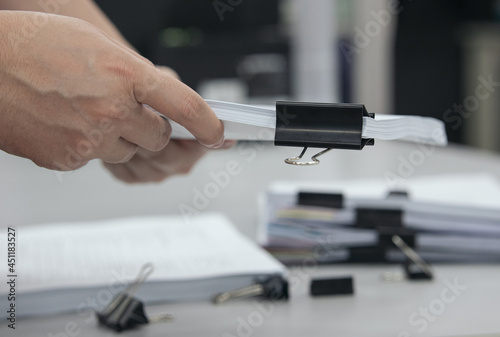Hands using the Black Paper clips for paper documents in the office. Office essential tools for paperwork
