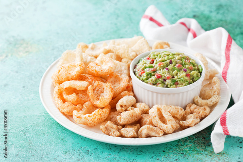 Guacamole avocado dip with Pork Rinds chicharron on a white plate photo