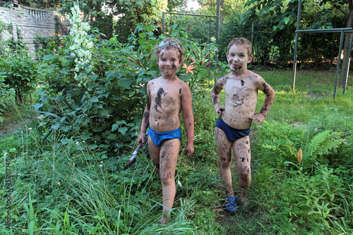 Two boys posing soiled in mud