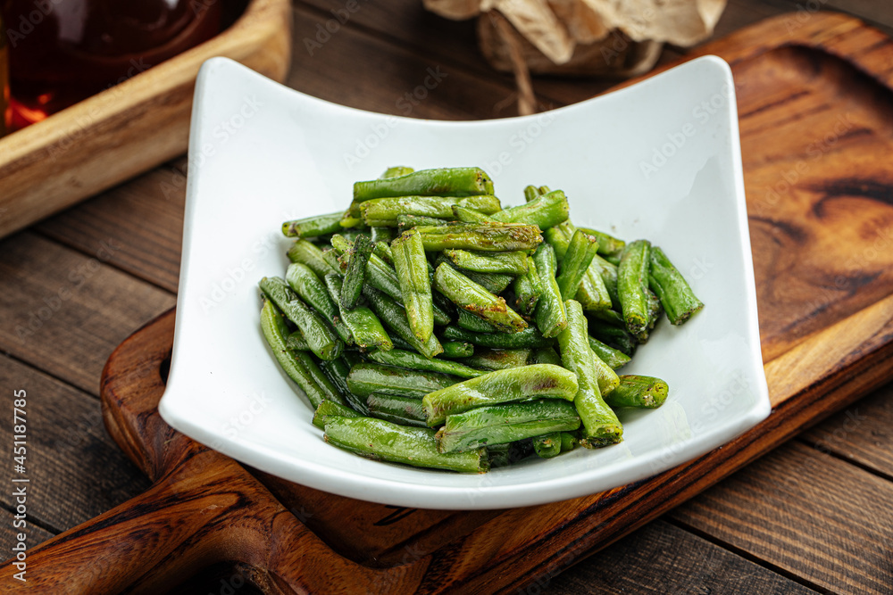 Plate of fried green string beans garnish on a wooden background