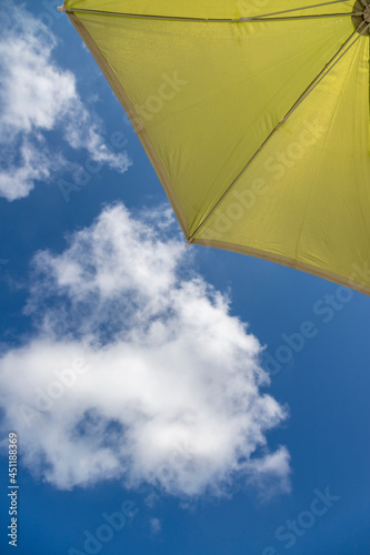  Blue beach umbrella with blue sky background and white clouds.