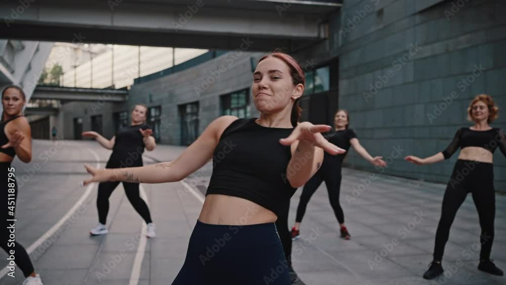 New zumba, modern sports dances. Energetic and active woman trainer leads a Zumba class in the middle of a city street New zumba, modern sports dances. Energetic and active woman trainer leads a Zumba class in the middle of a city street