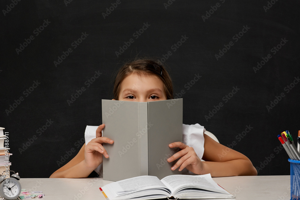 Obraz premium little child girl cover her face by the book
