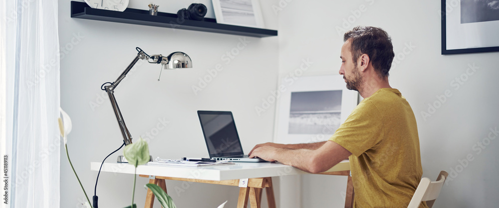 Adult caucasian man working on a laptop at home.