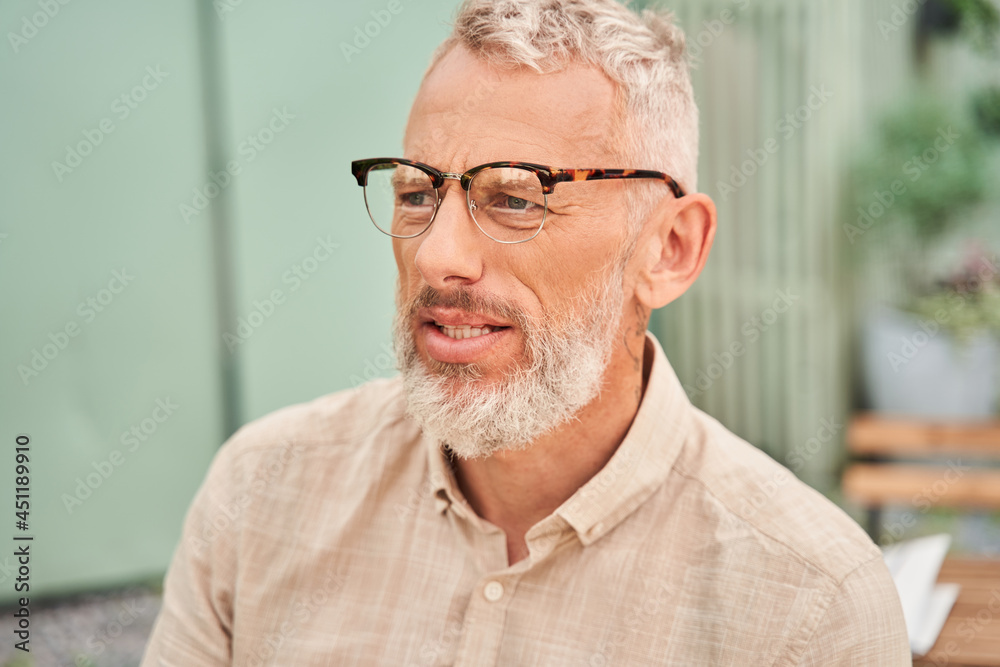Man wearing glasses enjoying of the warm morning while sitting at the cafe Man wearing glasses enjoying of the warm morning while sitting at the cafe
