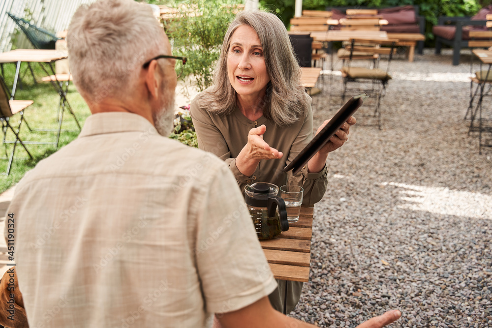 Woman telling something emotionally to her husband while holding tablet Woman telling something emotionally to her husband while holding tablet