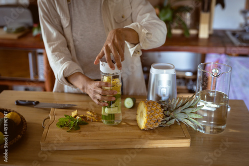 Mixed race woman preparing healthy drink in kitchen