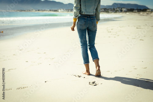 Mixed race woman walking at beach on sunny day