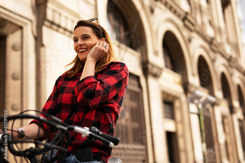 Young blonde woman on bicycle on the street. Beautiful girl talking to the phone