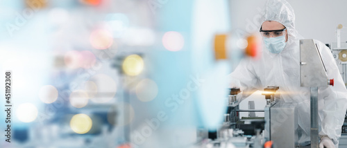 Scientists wearing protective clothing Inspect mask making machines in a laboratory at an industrial plant. Anti-virus production warehouse. concept of safety and prevention coronavirus covid-19.