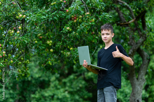 Boy giving thumbs up and studying with laptop in the park, Outdoor learning concept