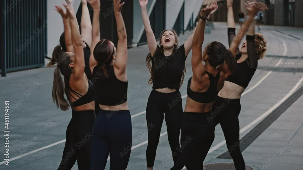 Young happy and active female sportswomen doing a group handshake after completing a training session or competition. Group of girls in sports uniforms celebrate the victory and clap their hands