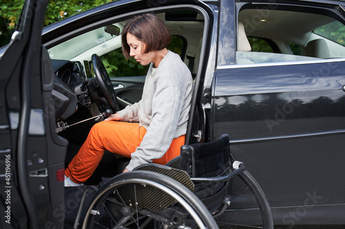 Obraz na plátne Disabled woman sitting on wheelchair boarding into her car