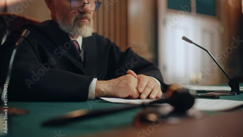 Court of Law and Justice Trial: Honorable Male Judge Discussing Pleaded Case, Explaining His Deliberations, Decision of Innocent Verdict after Hearing Arguments. Dramatic Focus on Hand Gestures photo
