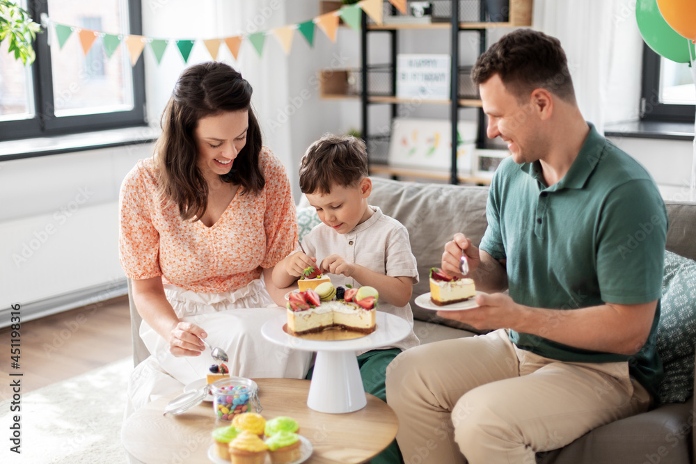 family, holidays and people concept - portrait of happy mother, father and little son eating birthday cake at home party party