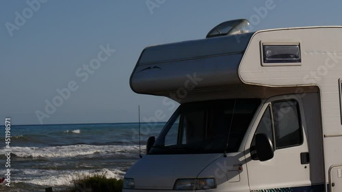 Santa Pola, Valencia, Spain - December 6, 2019: Autocaravan camping on sea shore. Sea waves moving in slow motion. Spain, Costa Blanca. photo