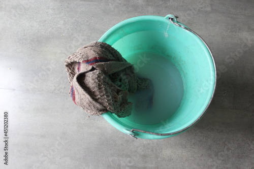 Little dirty bucket with cleaning solution and floor cloth. household cleaning products.  Housekeeping concept. Trash sweeping.  photo