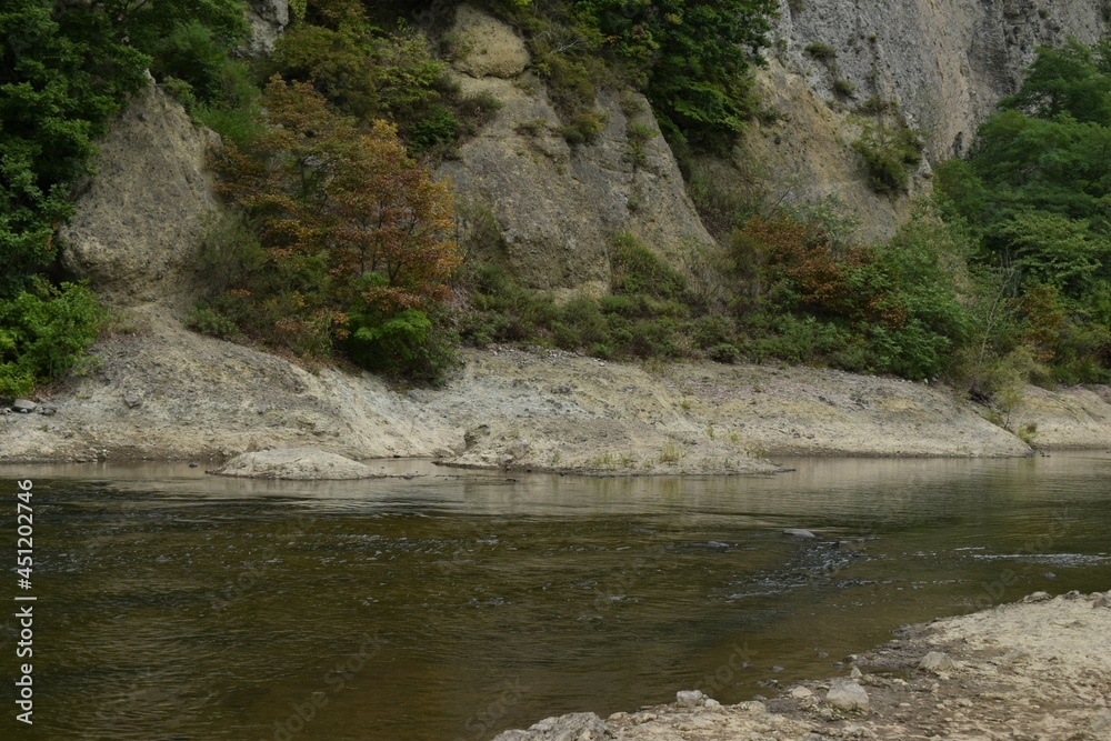 The beautiful rock mountain with the early autumn colored trees along with the Toyohira river in Sapporo Japan The beautiful rock mountain with the early autumn colored trees along with the Toyohira river in Sapporo Japan