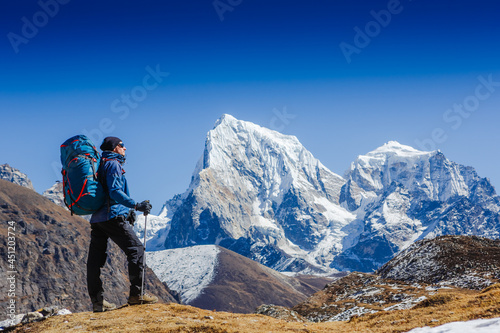Active hiker hiking, enjoying the view, looking at Himalaya mountains landscape. Travel sport lifestyle concept. Everest base camp trek