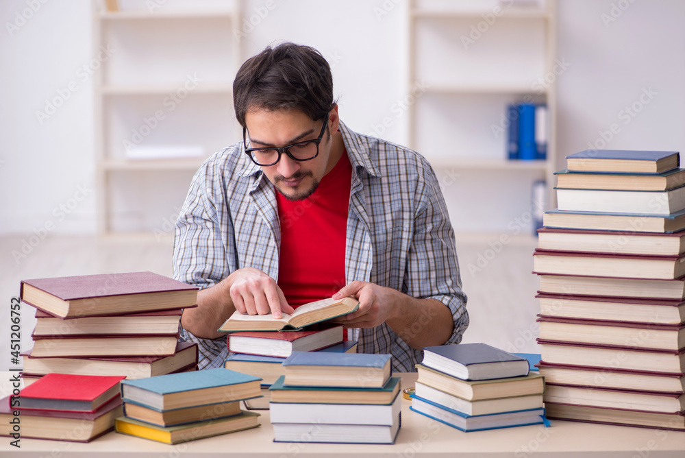 Young male student and too many books in the classroom Young male student and too many books in the classroom