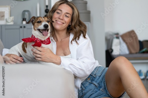 Young woman and her dog on sofa at home. Adorable pet.