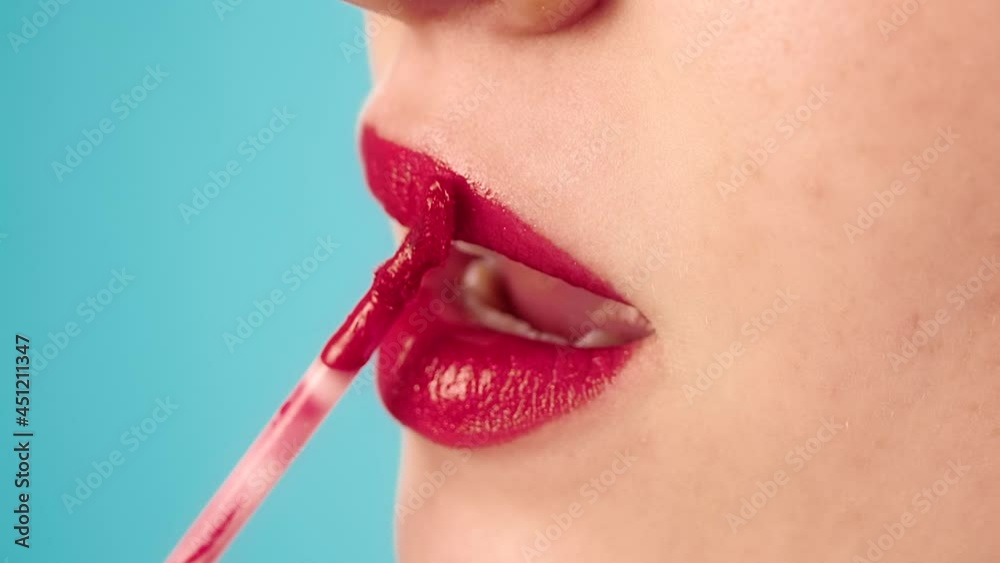 Concentrated model applies red lipstick on lips with special brush 
