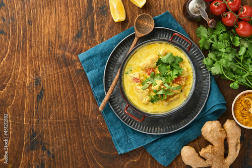 Chicken tikka masala. Traditional of indian cuisine curry and ingredients on dark background. Curry, lime, ginger, cilantro, chili, rice, herbs and spices. Top view with copy space.