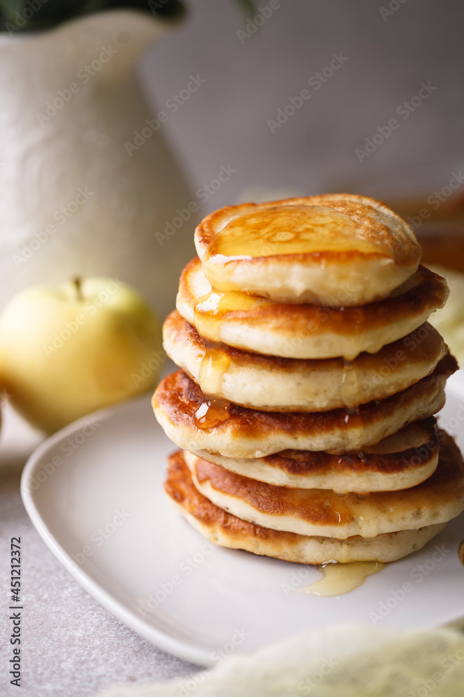 Stack of apple pancakes with pouring honey on white plate Stack of apple pancakes with pouring honey on white plate