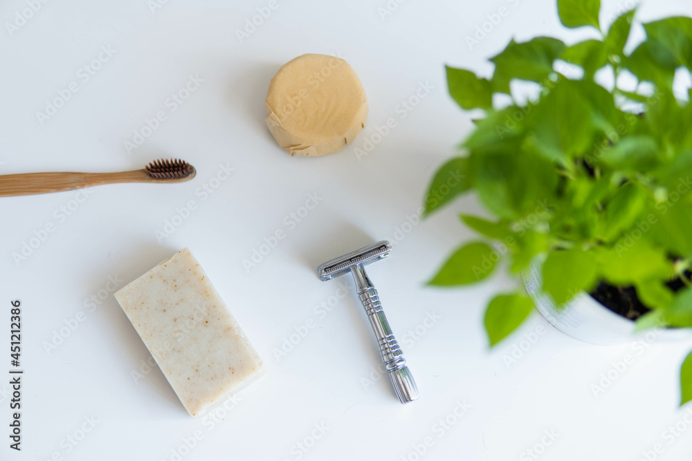 Zero waste product, close up caption. Bamboo toothbrush, solid shampoo, metal razor and solid hand soap. Sustainable bathroom products on a white background.