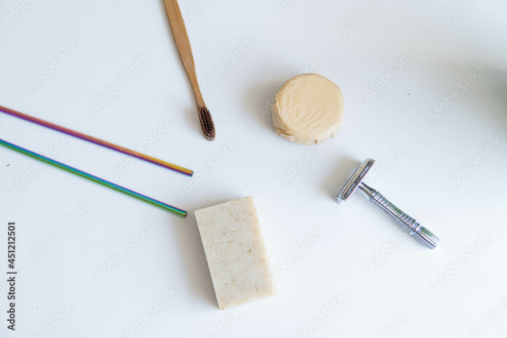 Zero waste product, close up caption. Bamboo toothbrush, solid shampoo, metal razor, metal straws and solid hand soap. Sustainable bathroom products on a white background.